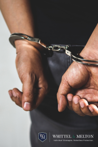 A close-up of a person's hands in handcuffs behind their back, symbolizing arrest or legal trouble. The image features the Whittel & Melton logo.